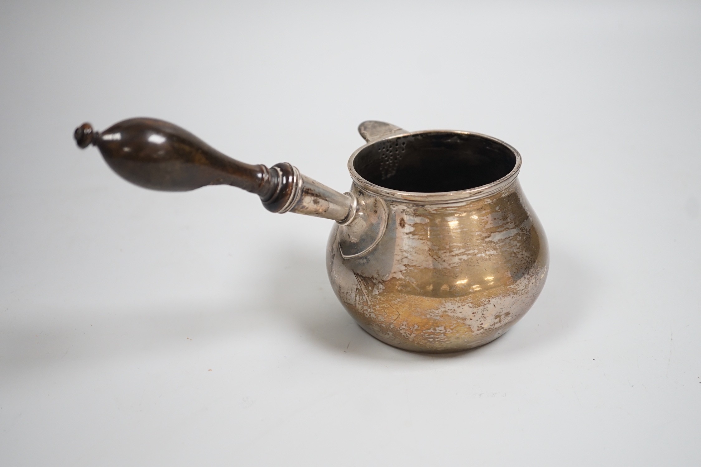 A late 18th/early 19th century white metal brandy warmer, with turned wooden handle and spout with hinged cover, stamped JH below an anchor, approx. 20cm in length, handle (a.f.).